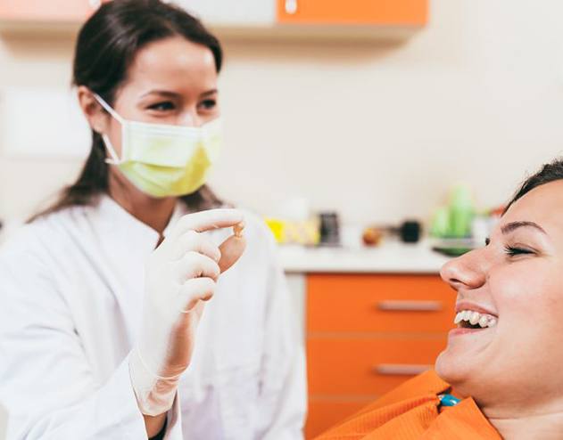 Patient smiling while dental team member holds extracted tooth